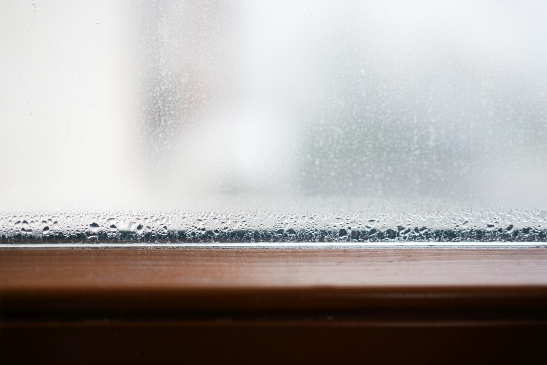 Water droplets and condensation on window glass indicating high indoor humidity levels